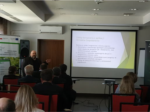 Adam Matyszczak z Mazowieckiego Ośrodka Doradztwa Rolniczego poprowadził wykład o praktycznym zastosowaniu Wirtualnego gospodarstwa Wnętrze pomieszczenia. Mężczyzna w średnim wieku, Adam Matyszczak, stoi obok rzutnika, na którym wyświetlana jest prezentacja.