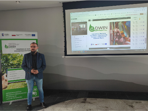 Kierownik projektu Maciej Zacharczuk z Wielkopolskiego Ośrodka Doradztwa Rolniczego w Poznaniu podsumował trzyletnie prace nad platformą eDWIN Maciej Zacharczuk, młody mężczyzna w niebieskiej marynarce, stoi pod ścianą. Po jego prawej stronie jest rollup promujący eDWIN, a po lewej stronie widoczna prezentacja wyświetlana na rzutniku.