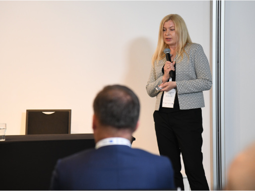 Anna Pietruczuk z Centrum Doradztwa Rolniczego w Brwinowie opowiadała o perspektywach dalszego rozwoju platformy eDWIN Młoda kobieta w szarej marynarce - Anna Pietruczuk - stoi z mikrofonem w ręku i wygłasza prezentację. Przed nią, od tyłu, widoczny jest słuchacz w marynarce.