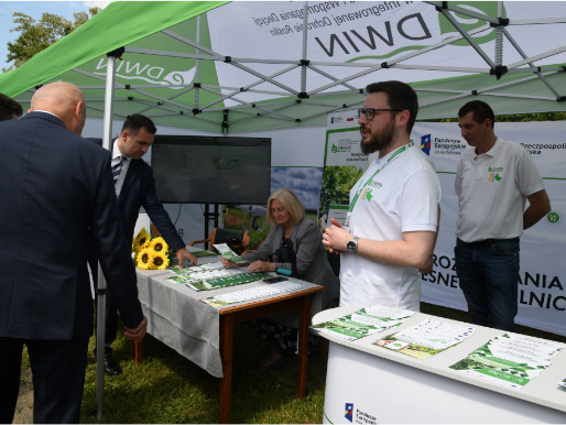 Na targach w Sielinku nie mogło zabraknąć stoiska z platformą eDWIN Wnętrze namiotu eDWIN. Pracownicy WODR stoją przy stołach, na których leżą ulotki eDWIN.
