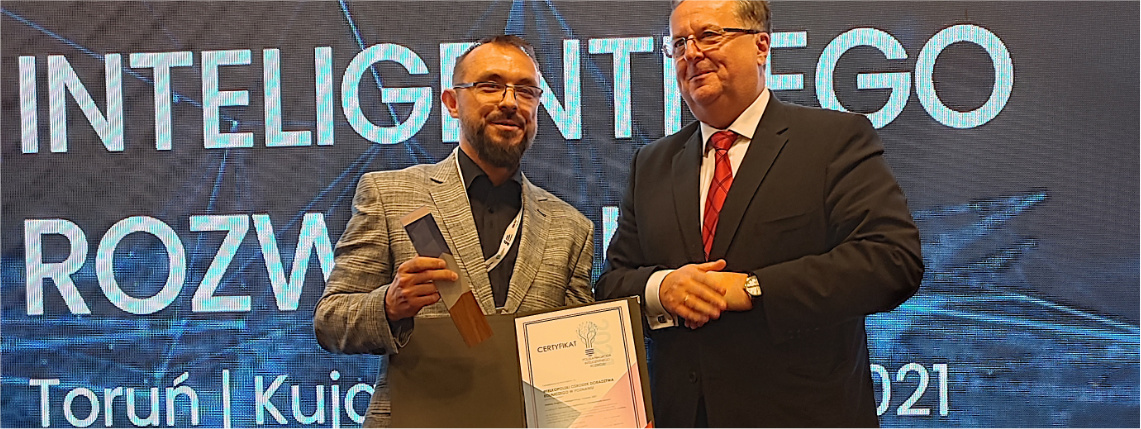 Maciej Zacharczuk, kierownik projektu eDWIN, odebrał Polską Nagrodę Inteligentnego Rozwoju, którą otrzymał Wielkopolski Ośrodek Doradztwa Rolniczego w Poznaniu Maciej Zacharczuk (po lewej) stoi obok mężczyzny w średnim wieku i trzyma nagrodę z dyplomem. Na niebieskim tle z tyłu jest napis "Forum Inteligentnego Rozwoju".