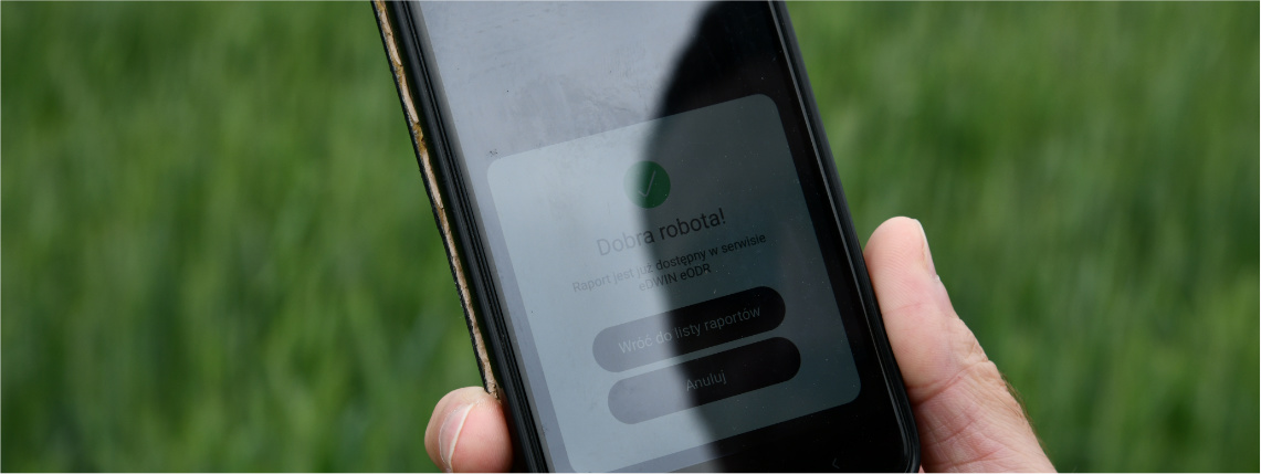Projekt eDWIN ma pomóc rolnikom w prowadzeniu gospodarstwa Zbliżenie na ekran telefonu, który znajduje się w dłoni. Na ekranie widać panel z napisem "Dobra robota! Raport jest już dostępny w serwisie eDWIN eODR". Poniżej są przyciski "wróć do listy raportów" oraz "anuluj".