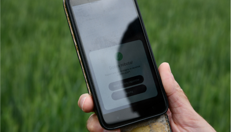 Projekt eDWIN ma pomóc rolnikom w prowadzeniu gospodarstwa Zbliżenie na ekran telefonu, który znajduje się w dłoni. Na ekranie widać panel z napisem "Dobra robota! Raport jest już dostępny w serwisie eDWIN eODR". Poniżej są przyciski "wróć do listy raportów" oraz "anuluj".
